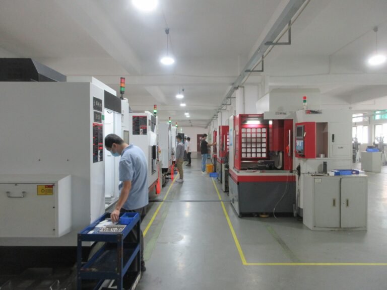 An operator at a large machine tool, a second machine with a red enclosure standing behind him
