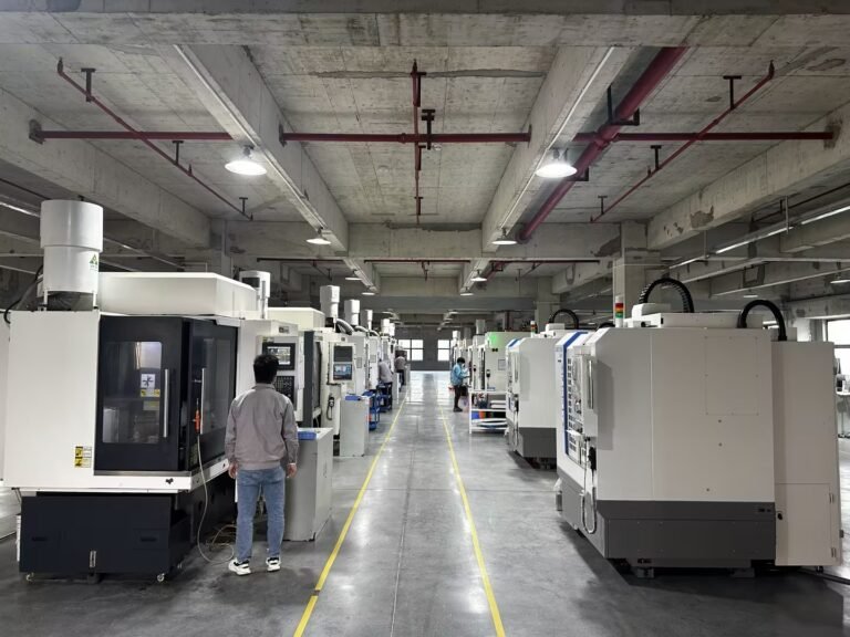 A machine hall seen down its length, CNC machining centres in rows under a travelling crane